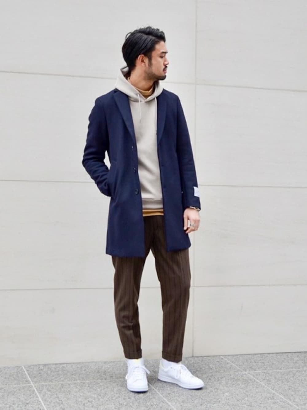 ブルー系のチェスターコート、ベージュ系のTシャツ/カットソー、ブラウン系のその他パンツを着用したメンズの冬コーディネートの1枚目の写真
