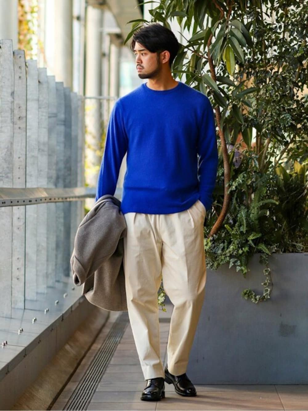 ブルー系のニット/セーター、ブラック系のドレスシューズ、グレー系のチェスターコートを着用したメンズの冬コーディネートの1枚目の写真