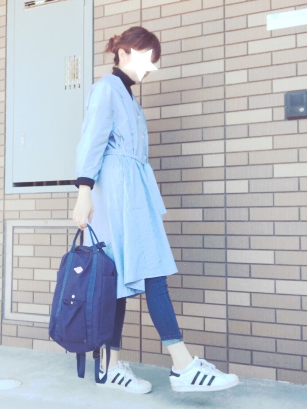 ブルー系のシャツワンピース、ブラック系のニット/セーター、ブルー系のデニムパンツを着用したレディースの春コーディネートの1枚目の写真