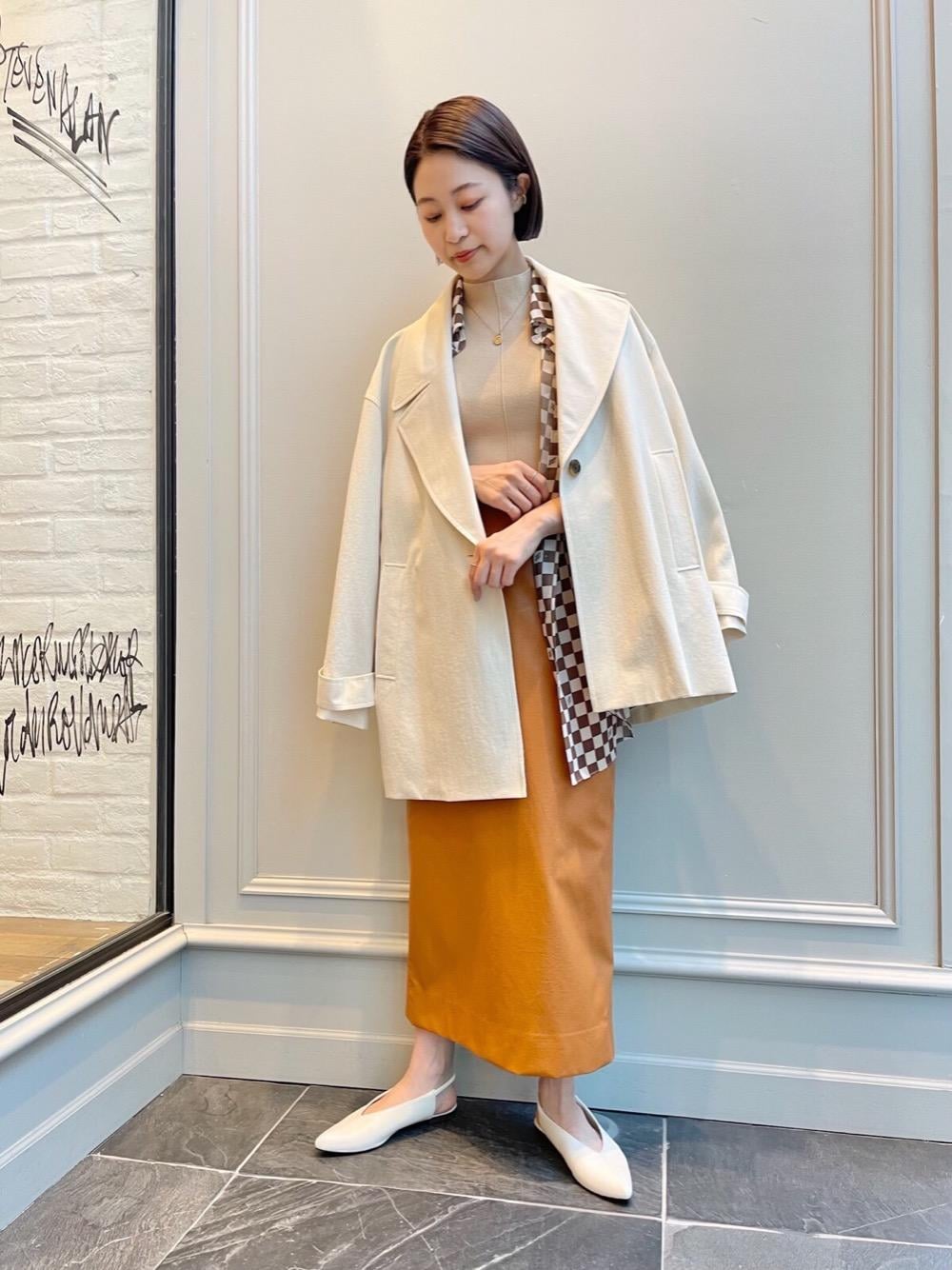 ベージュ系のニット/セーター、ホワイト系のパンプス、ブラウン系のシャツ/ブラウスを着用したレディースの冬コーディネートの1枚目の写真