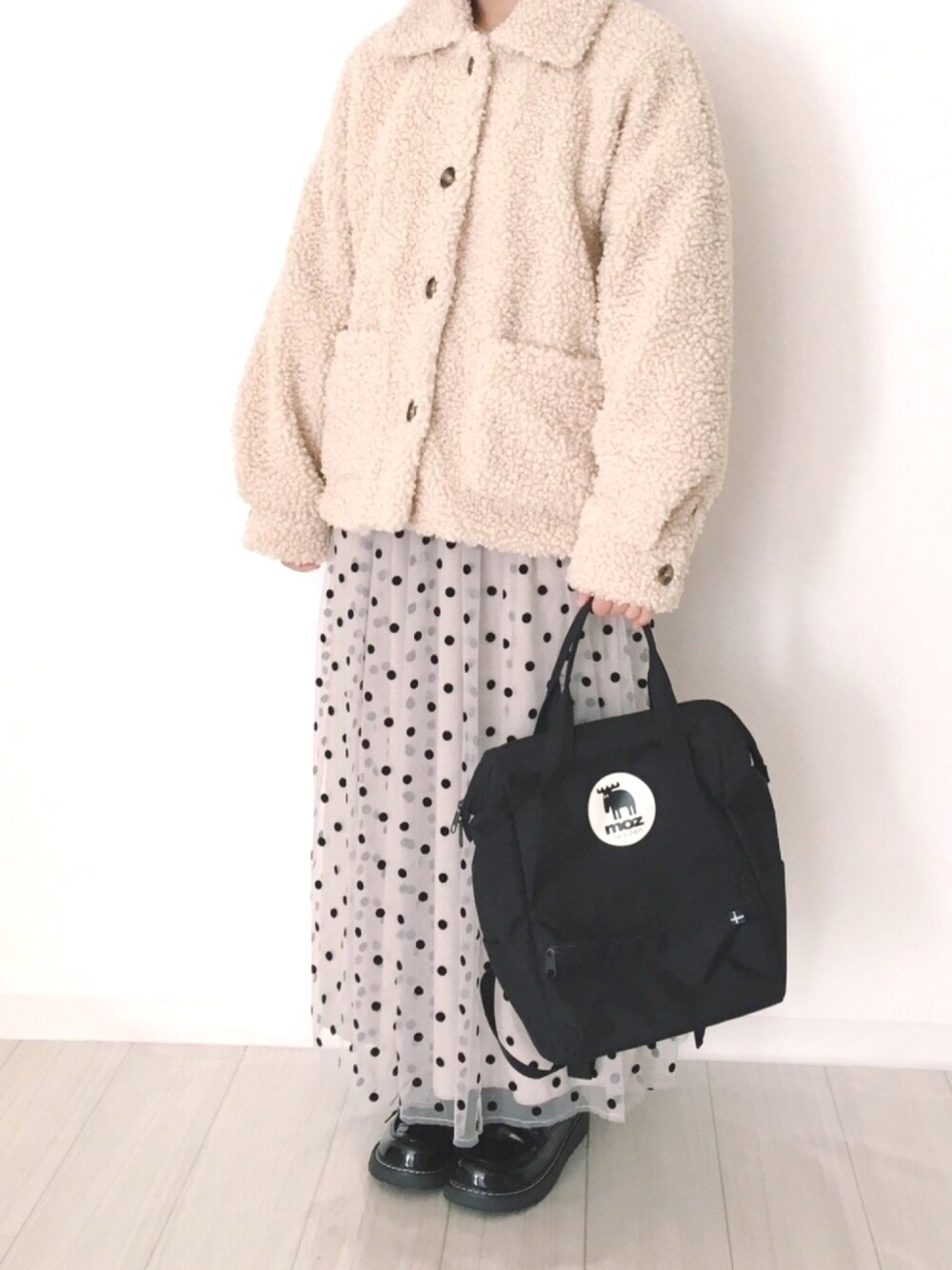 ホワイト系のジャケット/アウター、ブラック系のバックパック/リュック、ベージュ系のスカートを着用したレディースの冬コーディネートの1枚目の写真