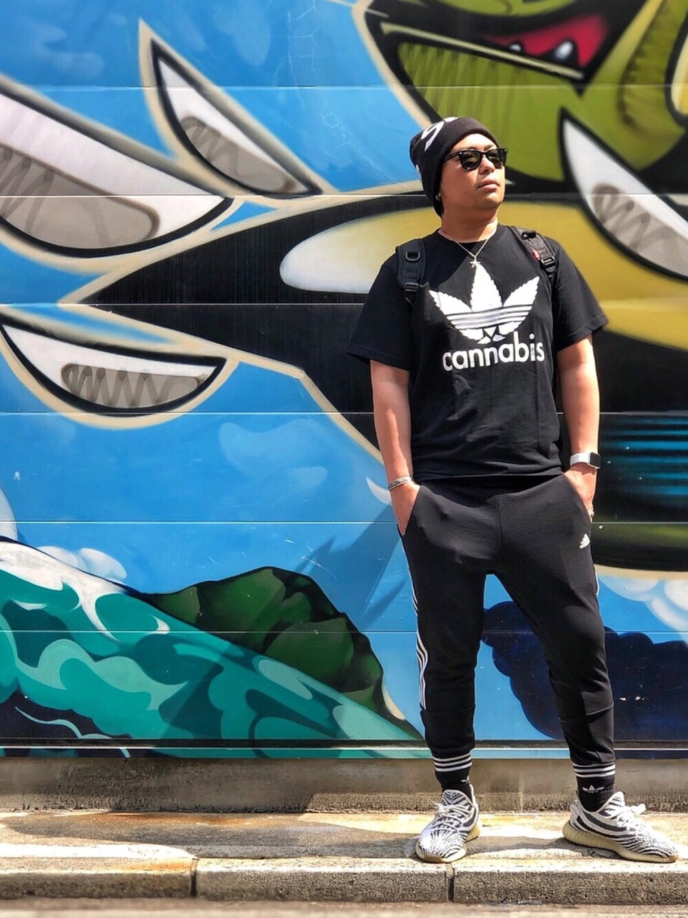 ブラック系のTシャツ/カットソー、ブラック系のその他パンツ、ホワイト系のスニーカーを着用したメンズの夏コーディネートの1枚目の写真