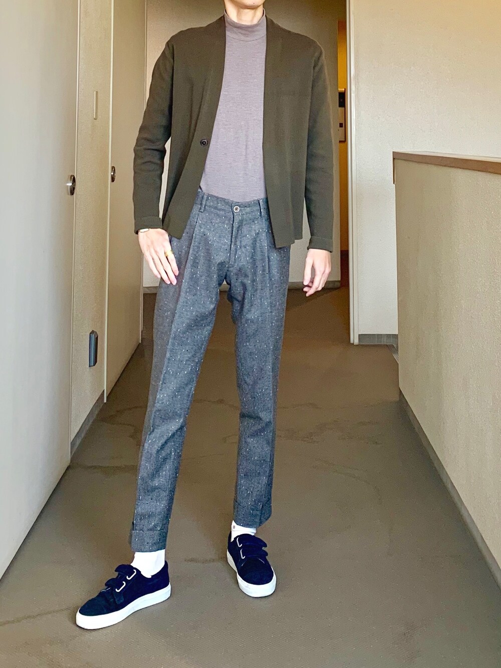 ブルー系のスニーカー、グレー系のスラックス、グリーン系のカーディガン/ボレロを着用したメンズの秋コーディネートの1枚目の写真