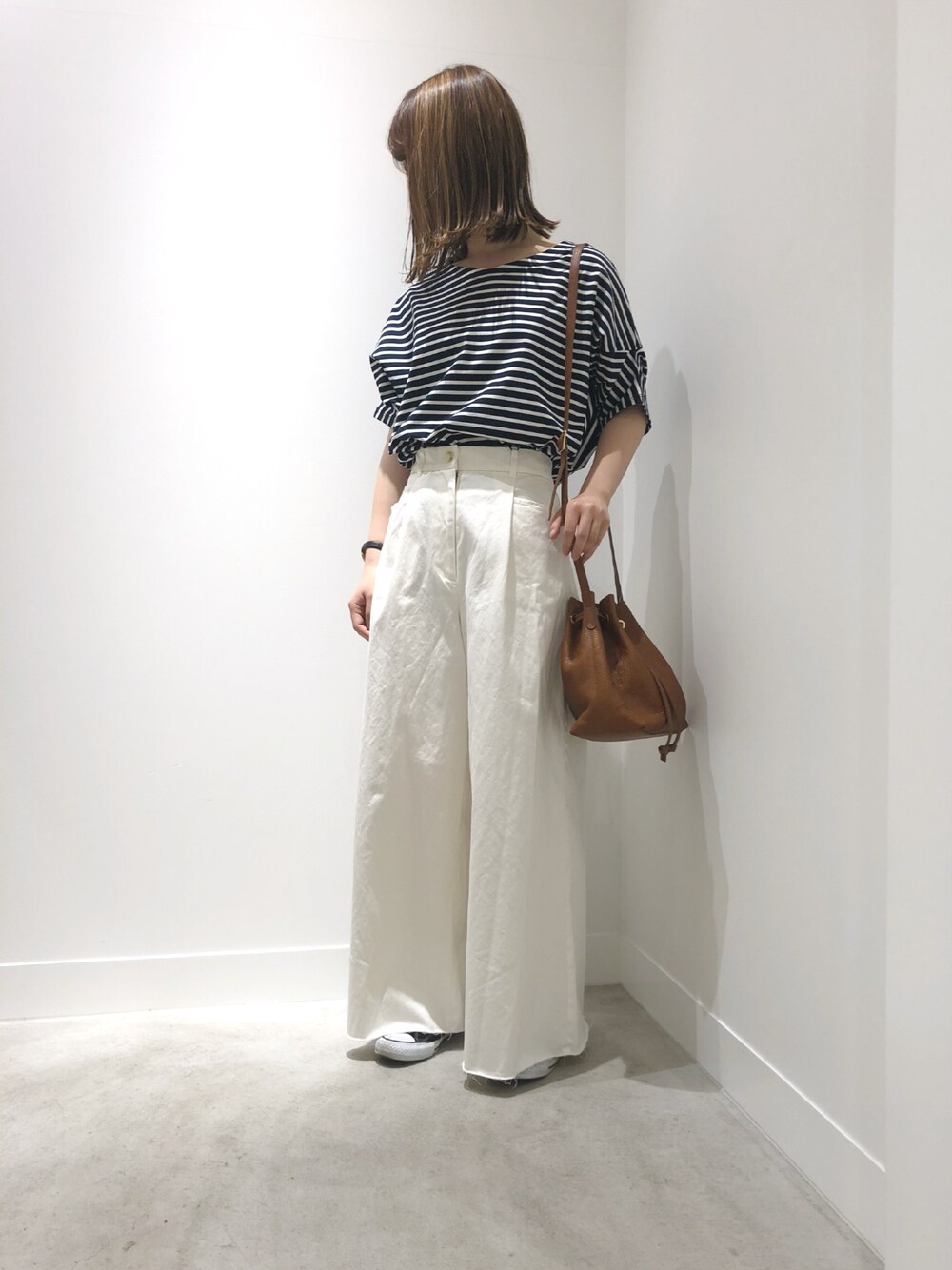 ブラック系のトップス、ホワイト系のパンツ、ホワイト系のスニーカーを着用したレディースの春コーディネートの1枚目の写真