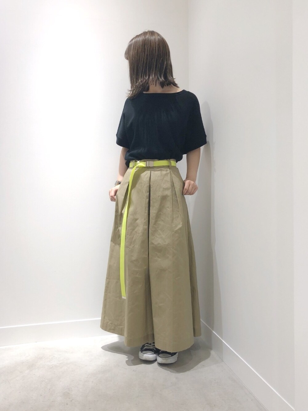 ブラック系のトップス、ベージュ系のパンツ、ブラック系のスニーカーを着用したレディースの春コーディネートの1枚目の写真