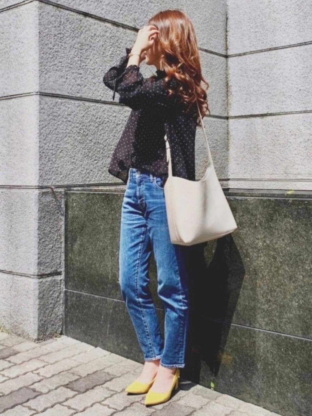 ブラック系のシャツ/ブラウス、ベージュ系のショルダーバッグ、ブルー系のデニムパンツを着用したレディースの春コーディネートの1枚目の写真