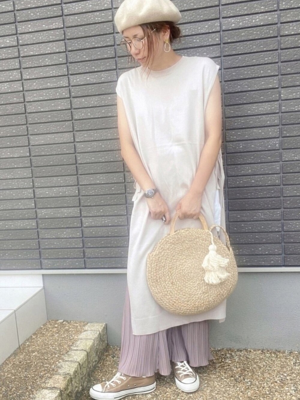 ベージュ系のベスト、ホワイト系のタンクトップ、ブラウン系のパンツを着用したレディースの夏コーディネートの1枚目の写真