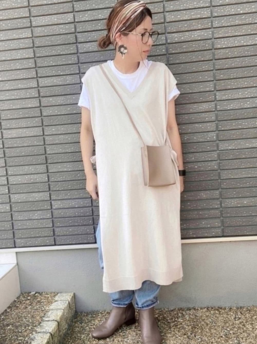 ベージュ系のベスト、ホワイト系のTシャツ/カットソー、ブルー系のデニムパンツを着用したレディースの夏コーディネートの1枚目の写真