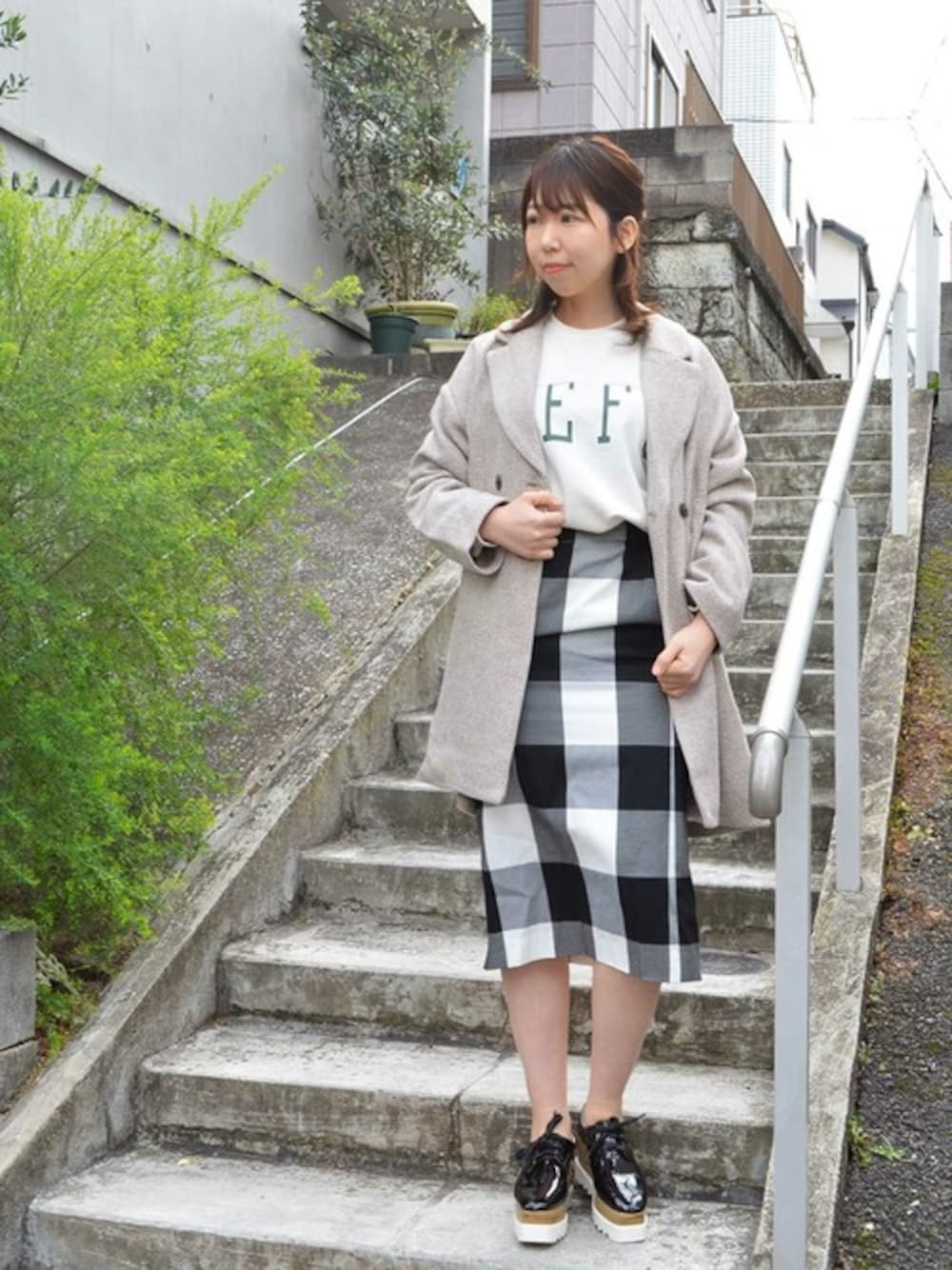 ベージュ系のチェスターコート、ホワイト系のスウェット、ブラック系のスカートを着用したレディースの冬コーディネートの1枚目の写真