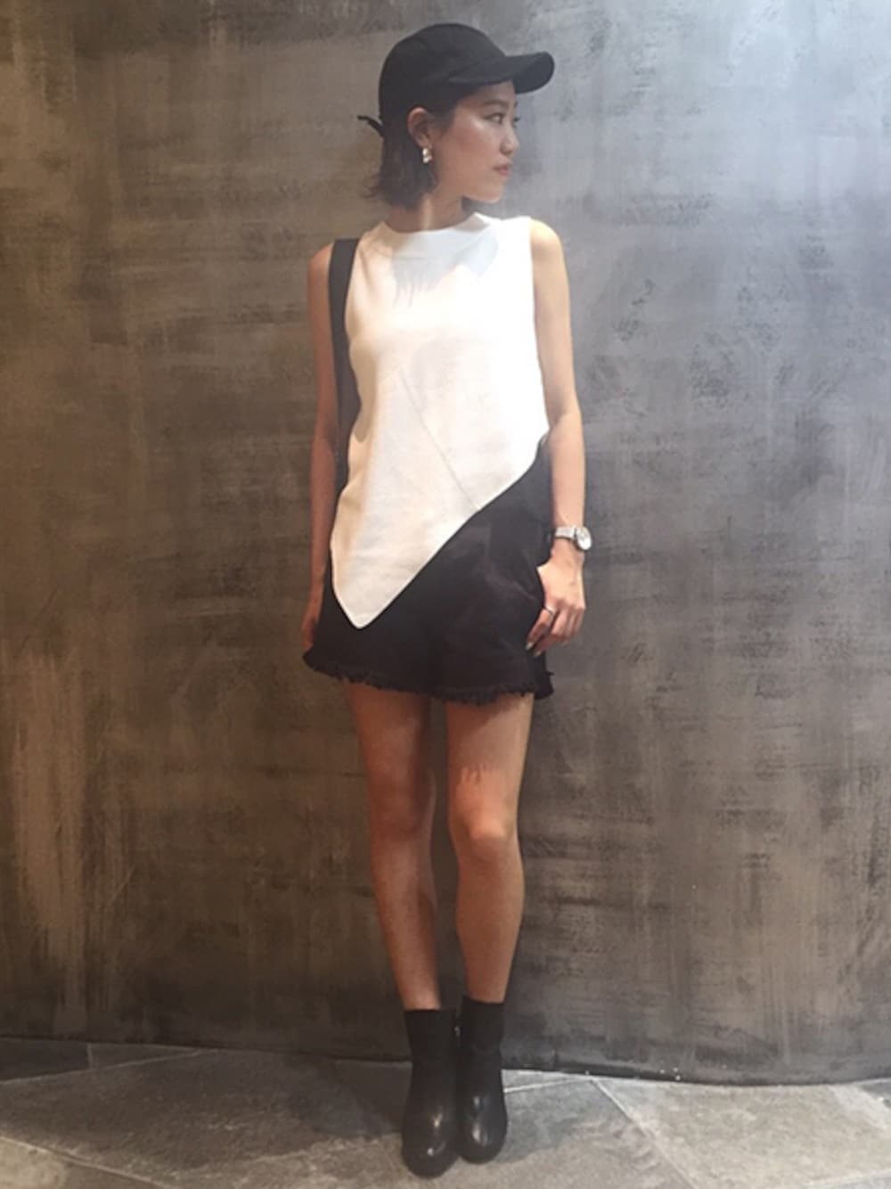 ホワイト系のタンクトップ、ブラック系のキャップを着用したレディースの秋コーディネートの1枚目の写真