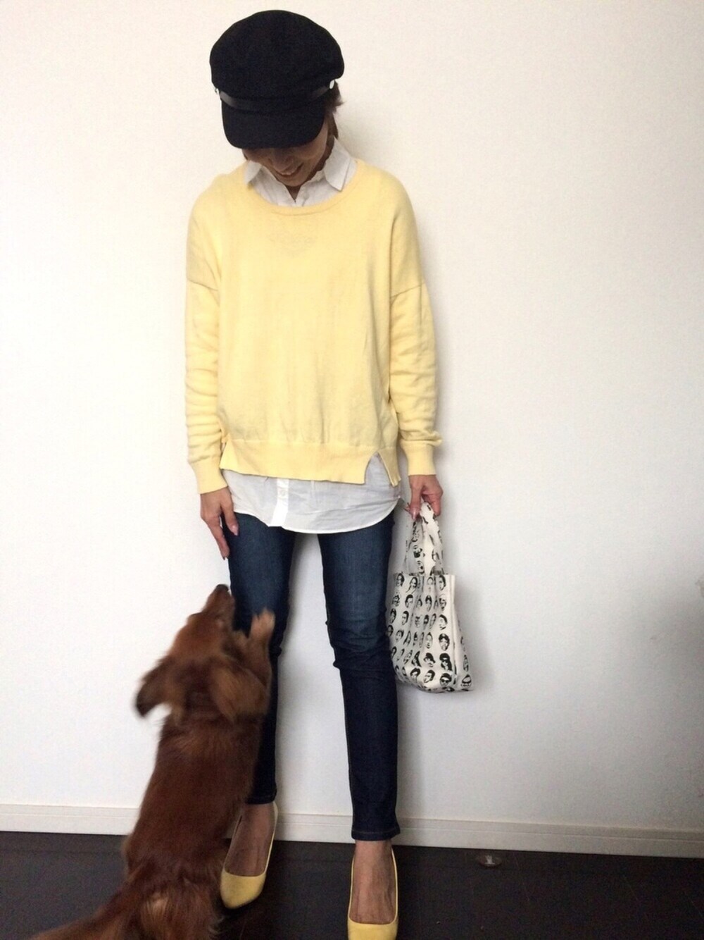 イエロー系のニット/セーター、ホワイト系のバッグ、ブラック系のキャスケットを着用したレディースの冬コーディネートの1枚目の写真