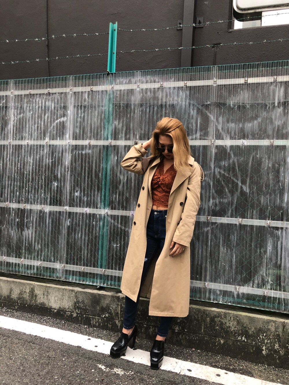 ベージュ系のトレンチコート、ブラウン系のTシャツ/カットソー、ブルー系のデニムパンツを着用したレディースの秋コーディネートの1枚目の写真