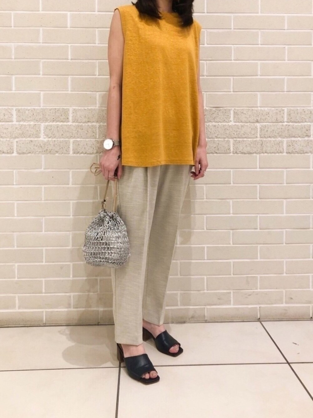グレー系のその他パンツ、シルバー系のショルダーバッグ、オレンジ系のTシャツ/カットソーを着用したレディースの夏コーディネートの1枚目の写真