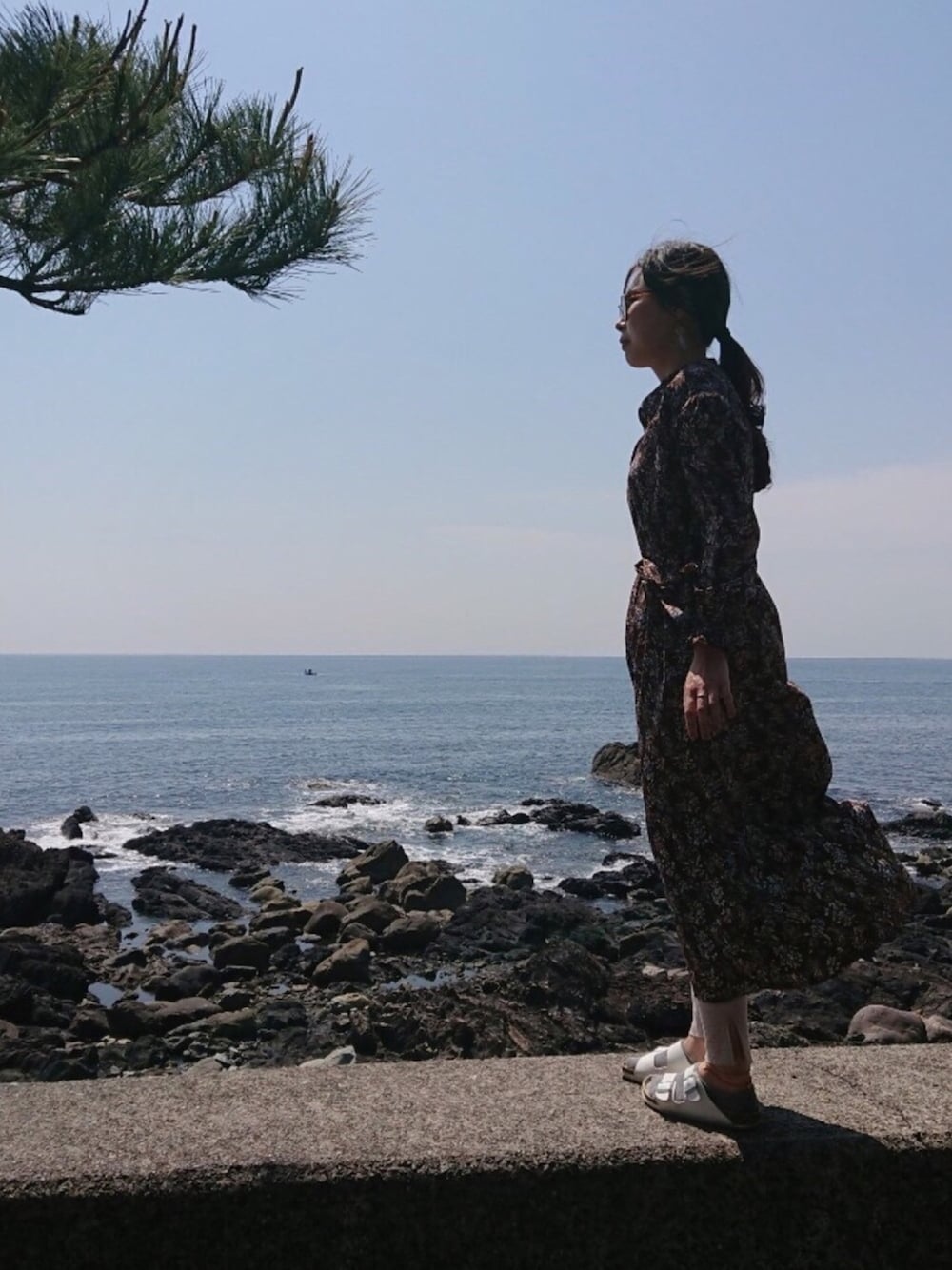 ブラウン系のワンピース、ホワイト系のサンダル、ブラウン系のサングラスを着用したレディースの春コーディネートの1枚目の写真