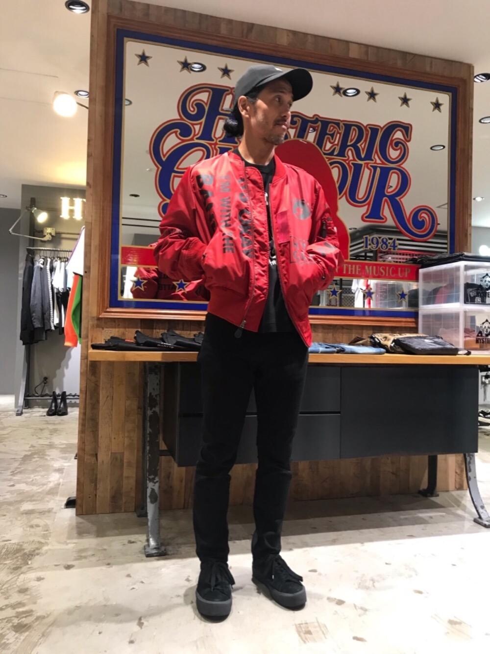 ブラック系のデニムパンツ、レッド系のミリタリージャケット、ブラック系のTシャツ/カットソーを着用したメンズの秋コーディネートの1枚目の写真