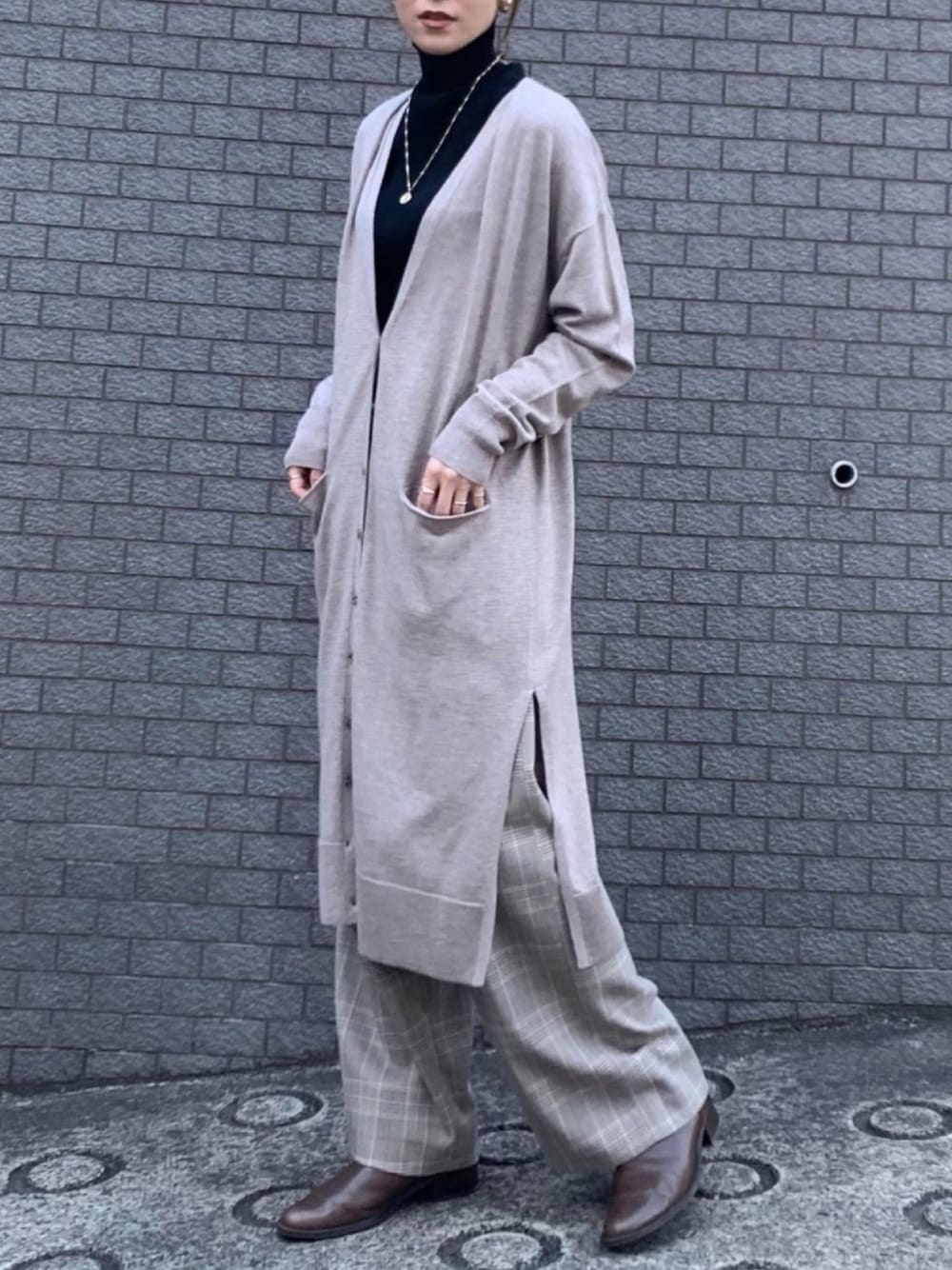 グレー系のスラックス、ブラック系のニット/セーター、ベージュ系のカーディガン/ボレロを着用したレディースの秋コーディネートの1枚目の写真