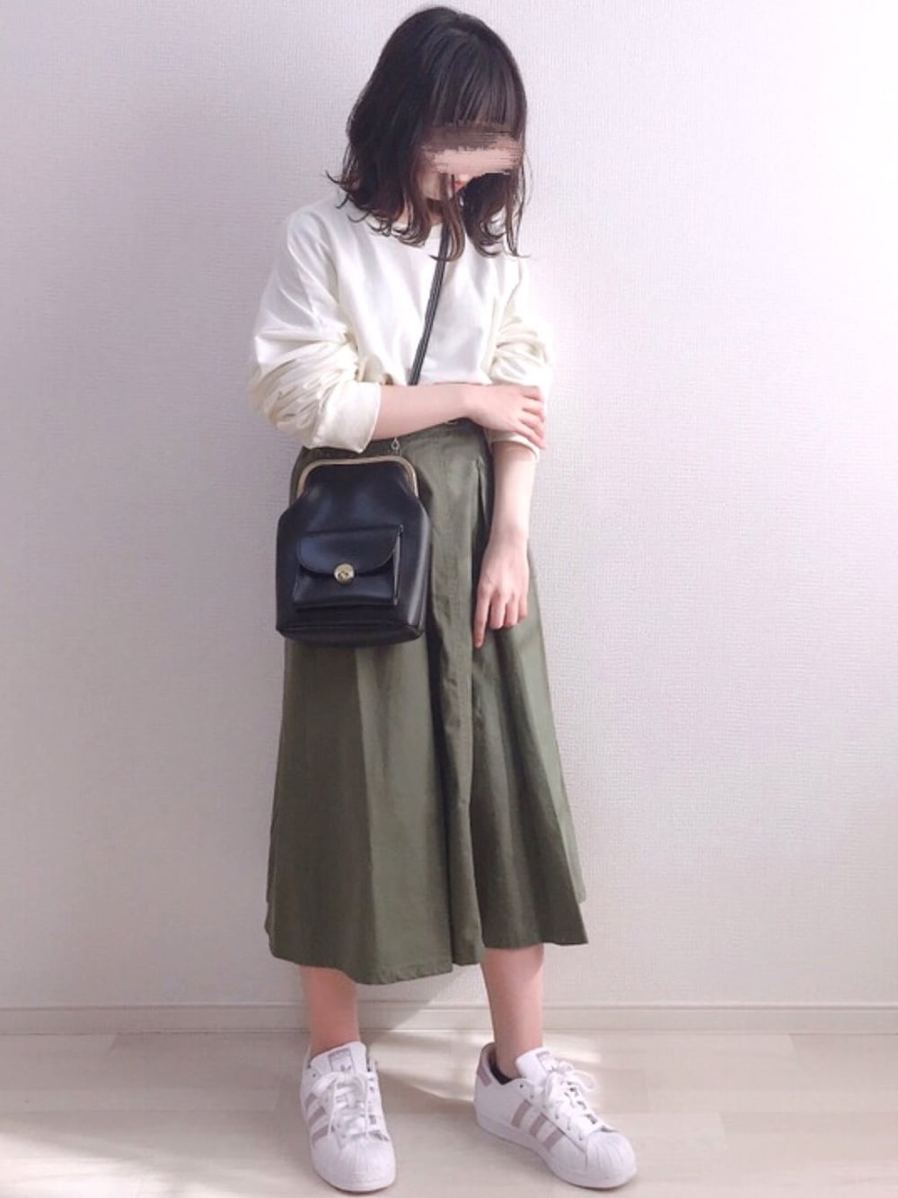 ホワイト系のスウェット、ブラック系のショルダーバッグ、グリーン系のスカートを着用したレディースの春コーディネートの1枚目の写真