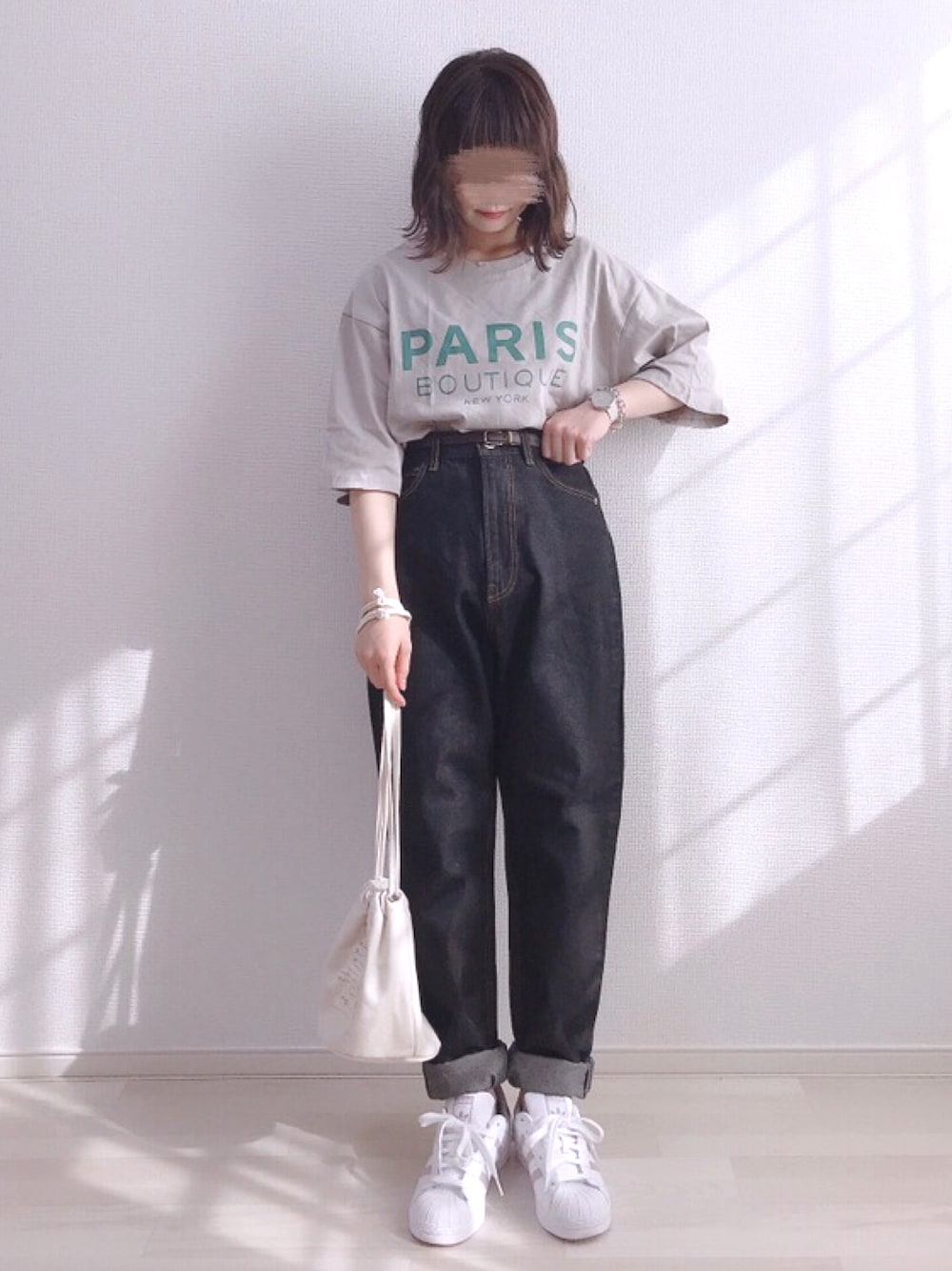 グレー系のTシャツ/カットソー、ブラック系のデニムパンツ、ベージュ系のハンドバッグを着用したレディースの夏コーディネートの1枚目の写真