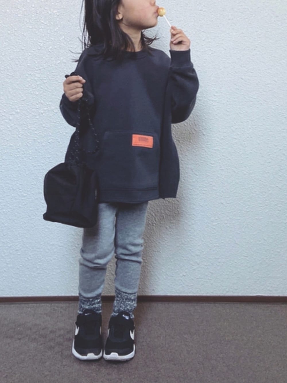 グレー系のスウェット、ブラック系のトートバッグ、ブラック系のスニーカーを着用したキッズの冬コーディネートの1枚目の写真