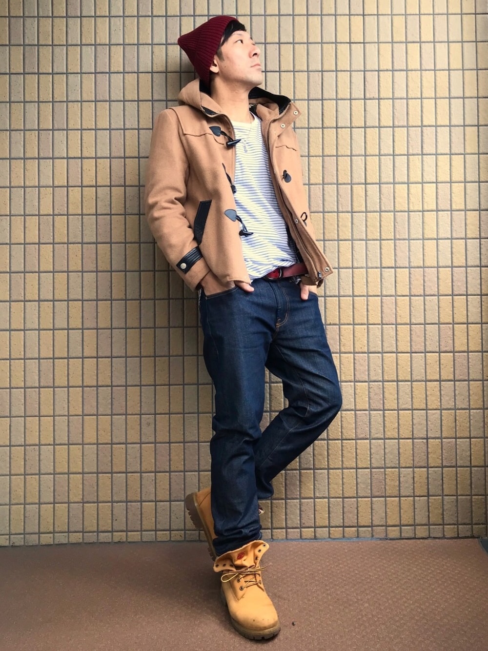 ベージュ系のダッフルコート、ホワイト系のTシャツ/カットソー、ブルー系のデニムパンツを着用したメンズの冬コーディネートの1枚目の写真