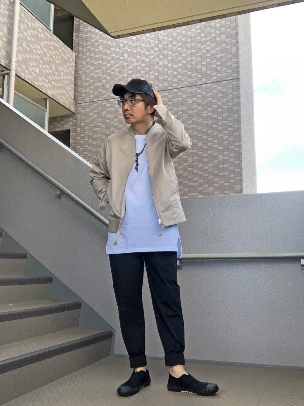 ホワイト系のTシャツ/カットソー、ベージュ系のその他アウター、ブラック系のスニーカーを着用したメンズの春コーディネートの1枚目の写真