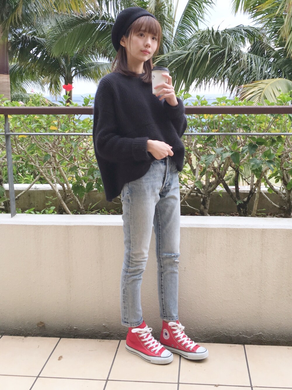 ブルー系のデニムパンツ、ブラック系のニット/セーター、レッド系のスニーカーを着用したレディースの冬コーディネートの1枚目の写真