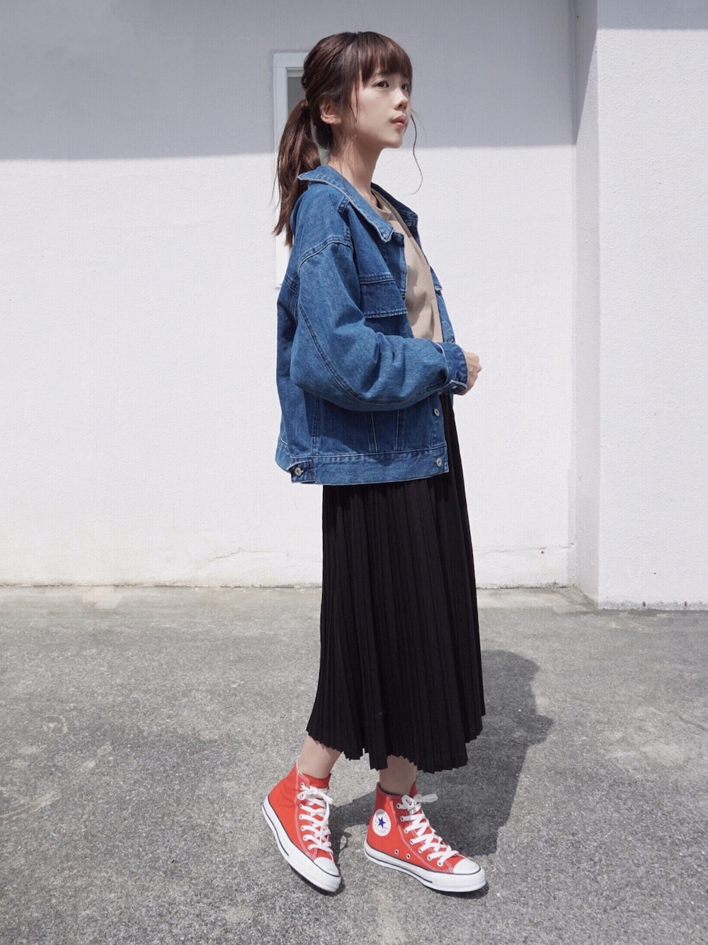 ブルー系のデニムジャケット、ブラウン系のTシャツ/カットソー、ブラック系のスカートを着用したレディースの春コーディネートの1枚目の写真