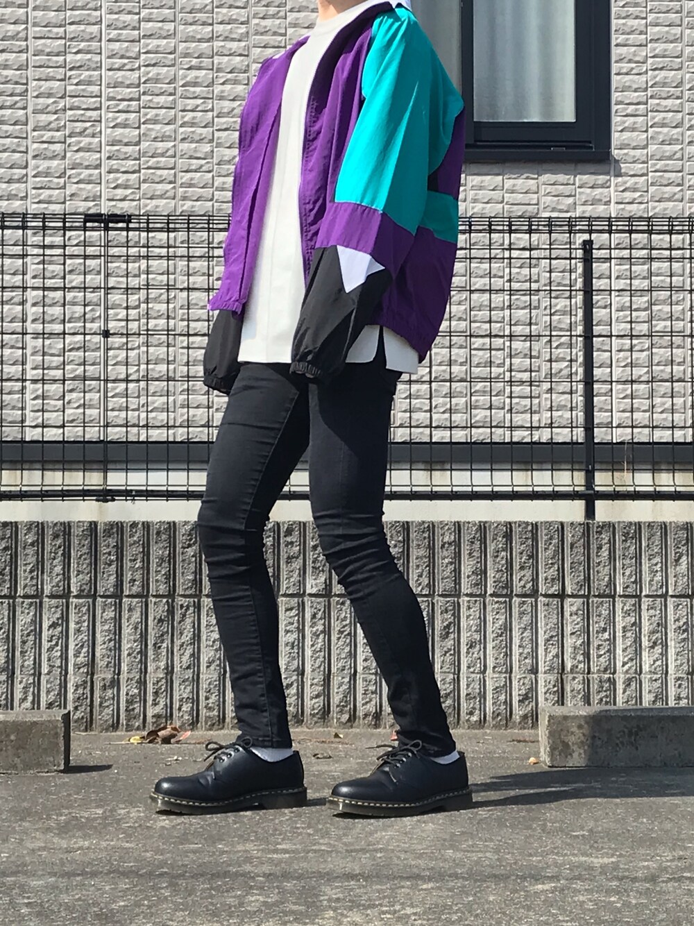 ブラック系のデニムパンツ、ブラック系のドレスシューズ、ホワイト系のニット/セーターを着用したメンズの春コーディネートの1枚目の写真