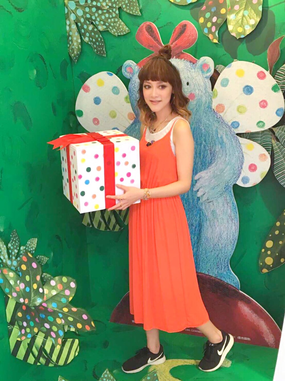 オレンジ系のワンピース、ブラック系のスニーカー、ゴールド系のブレスレットを着用したレディースの夏コーディネートの1枚目の写真