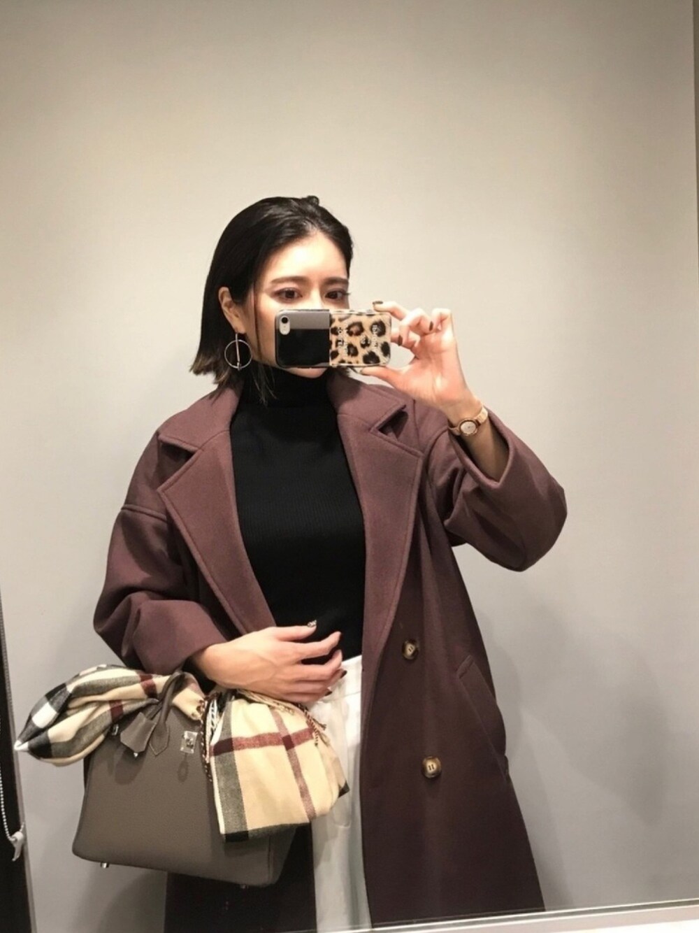 パープル系のチェスターコート、ゴールド系のアナログ腕時計、シルバー系のピアス（両耳用）を着用したレディースの秋コーディネートの1枚目の写真