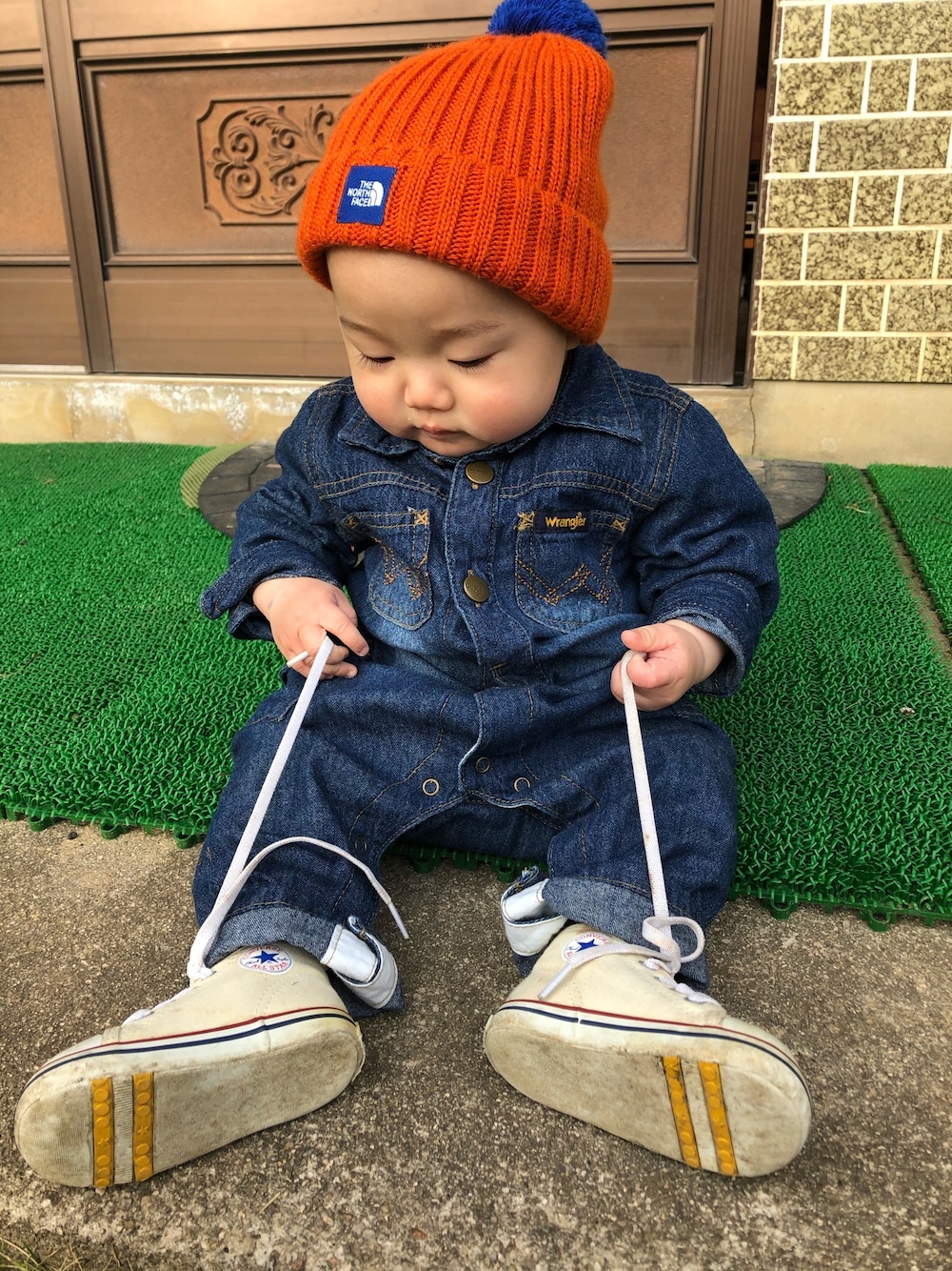 「男の子コーデ、ベビーコーデ、ロンパース、ザノースフェイス、ニットキャップ、コンバース、ファーストシューズ、デニムコーデ」｜「THE NORTH FACEのNNB41800ニットキャップ（ニットキャップ/ビーニー、オレンジ系）」を使った、ひなりのゆわさん（キッズ・100cm）の春コーディネートの1枚目の写真