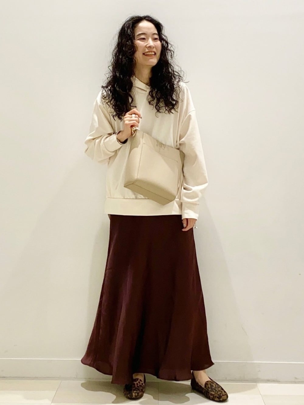 ベージュ系のショルダーバッグ、ブラウン系のスカート、その他のモカシン/デッキシューズを着用したレディースの秋コーディネートの1枚目の写真