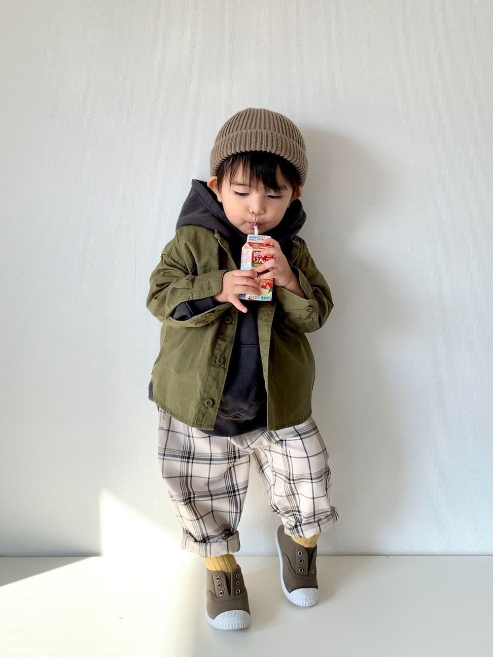 グリーン系のシャツ/ブラウス、ブラック系のパーカー、ホワイト系のパンツを着用したキッズの秋コーディネートの1枚目の写真