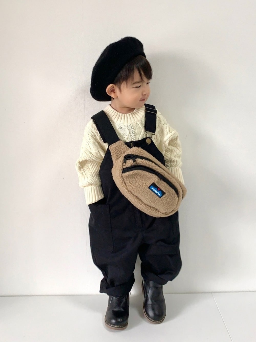 ホワイト系のニット/セーター、ブラック系のデニムパンツ、ブラック系のブーツを着用したキッズの冬コーディネートの1枚目の写真