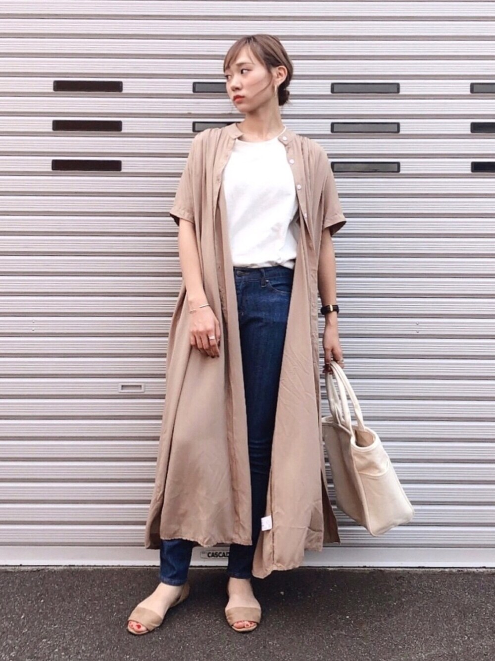 ベージュ系のシャツワンピース、ホワイト系のTシャツ/カットソー、ブルー系のデニムパンツを着用したレディースの夏コーディネートの1枚目の写真