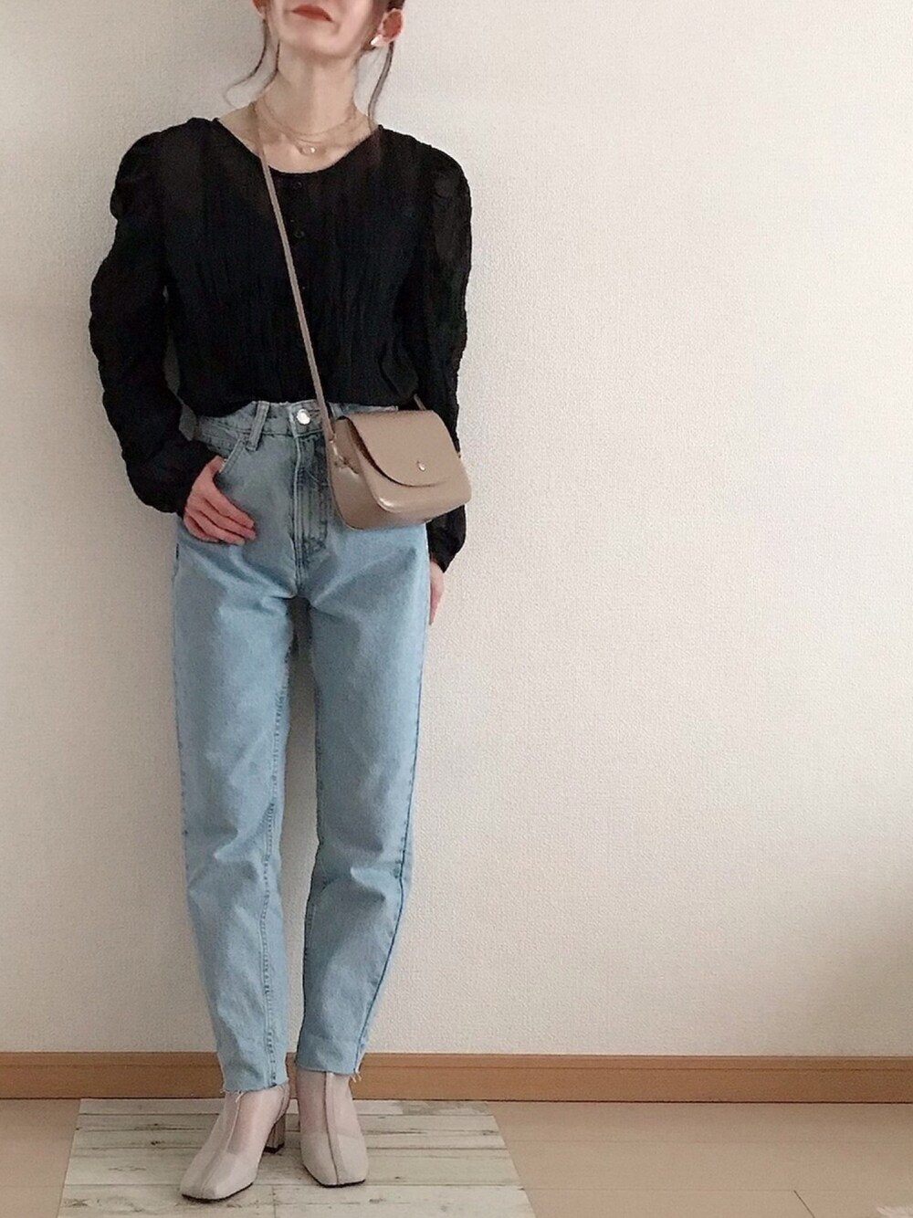 ベージュ系のブーツ、ブルー系のデニムパンツ、ベージュ系のショルダーバッグを着用したレディースの春コーディネートの1枚目の写真