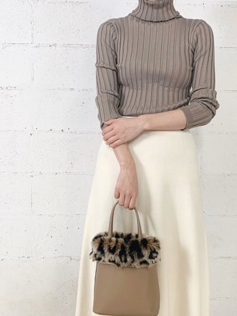 ブラウン系のニット/セーター、ホワイト系のスカートを着用したレディースの冬コーディネートの1枚目の写真