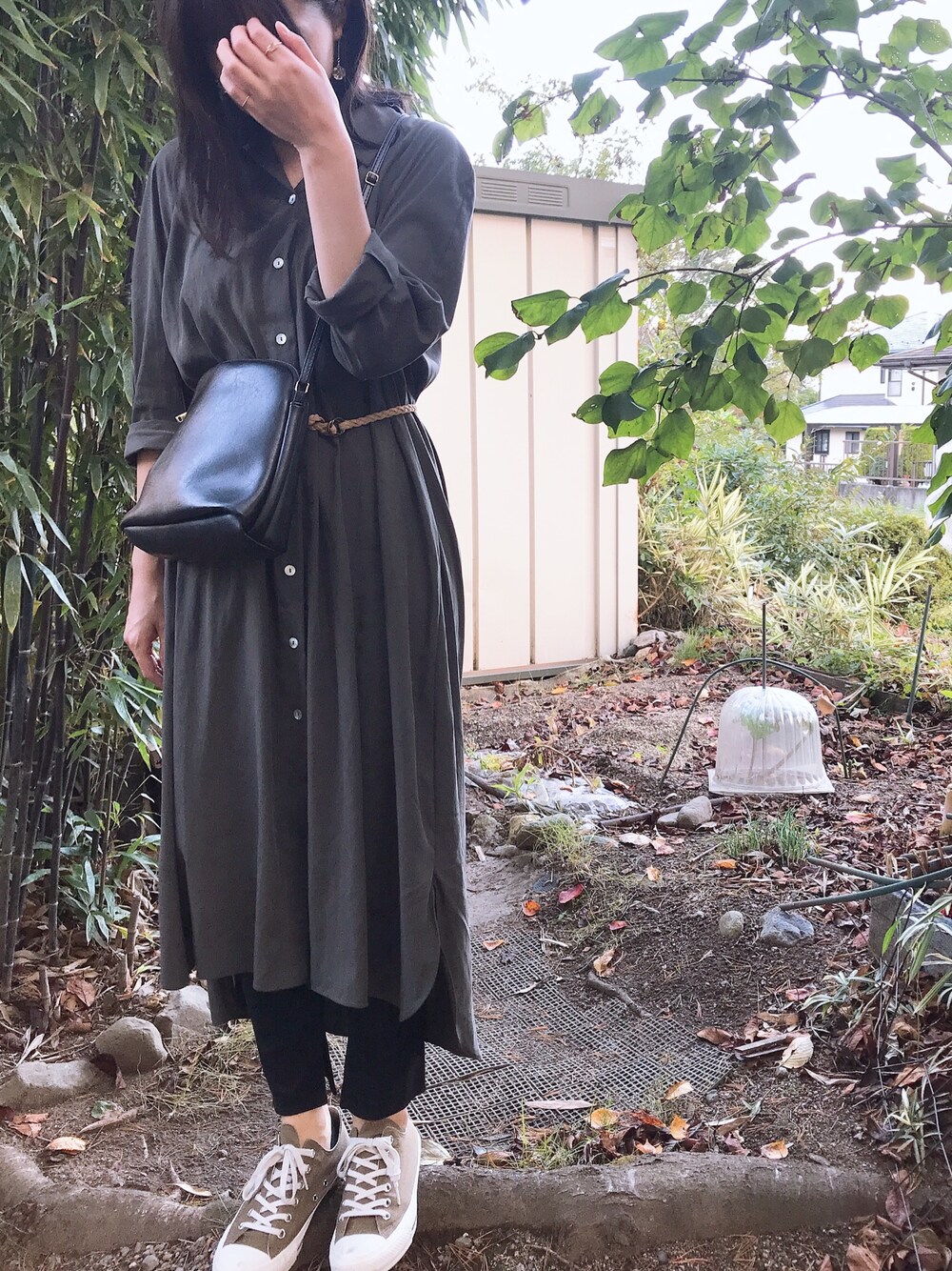 グリーン系のシャツワンピース、ベージュ系のスニーカーを着用したレディースの秋コーディネートの1枚目の写真