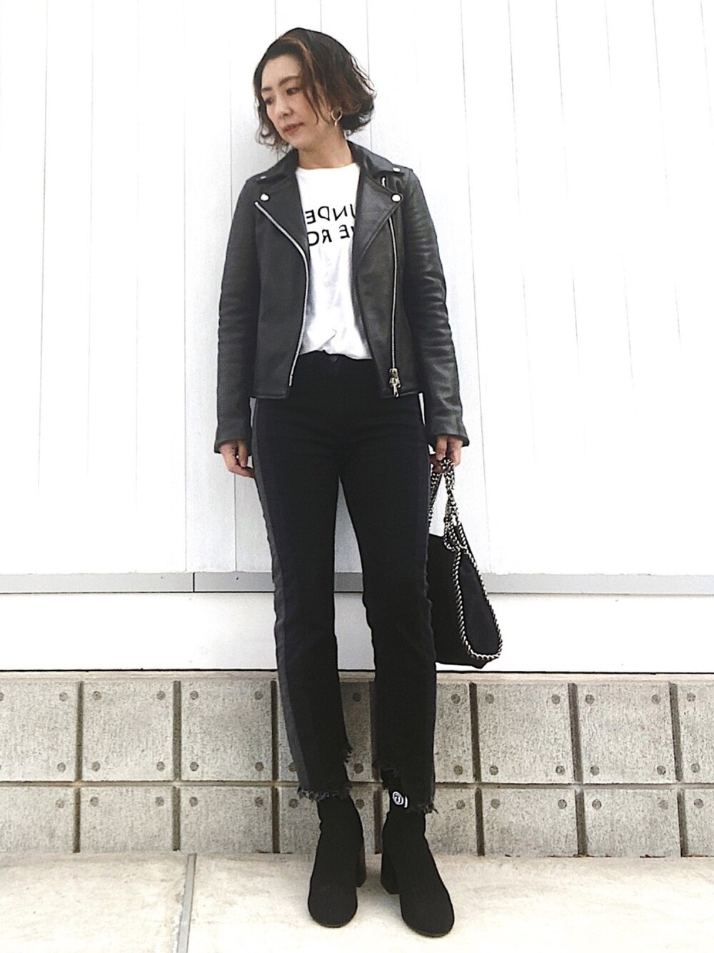 ブラック系のデニムパンツ、ブラック系のブーツ、ブラック系のショルダーバッグを着用したレディースの春コーディネートの1枚目の写真