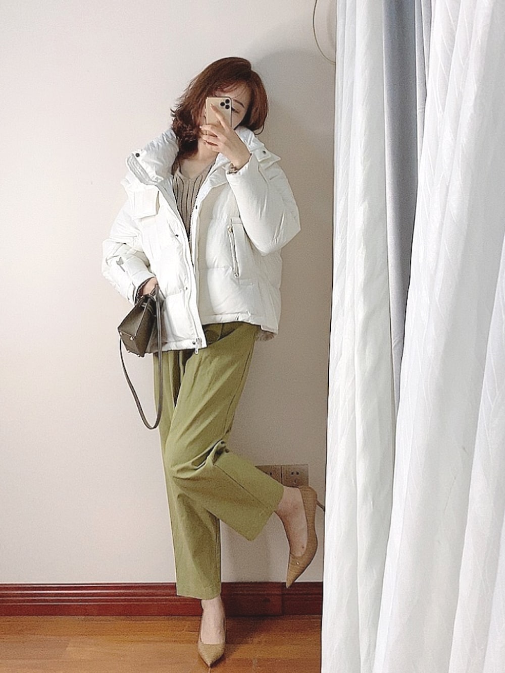 ホワイト系のダウンジャケット/コート、ベージュ系のニット/セーター、グリーン系のチノパンツを着用したレディースの冬コーディネートの1枚目の写真