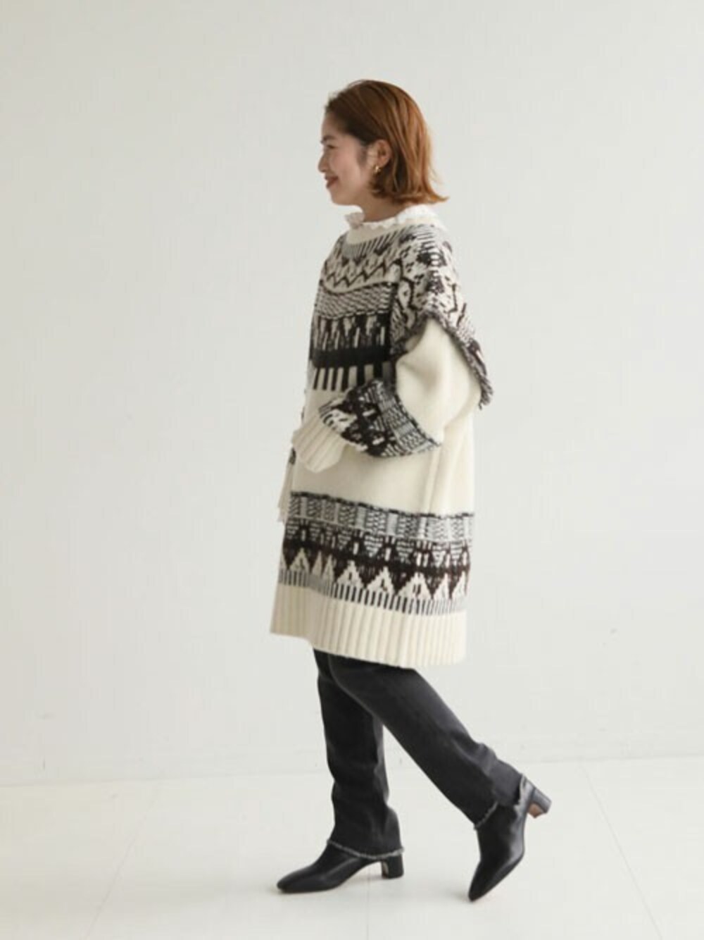 ホワイト系のニット/セーター、ブラック系のデニムパンツ、ブラック系のブーツを着用したレディースの秋コーディネートの1枚目の写真