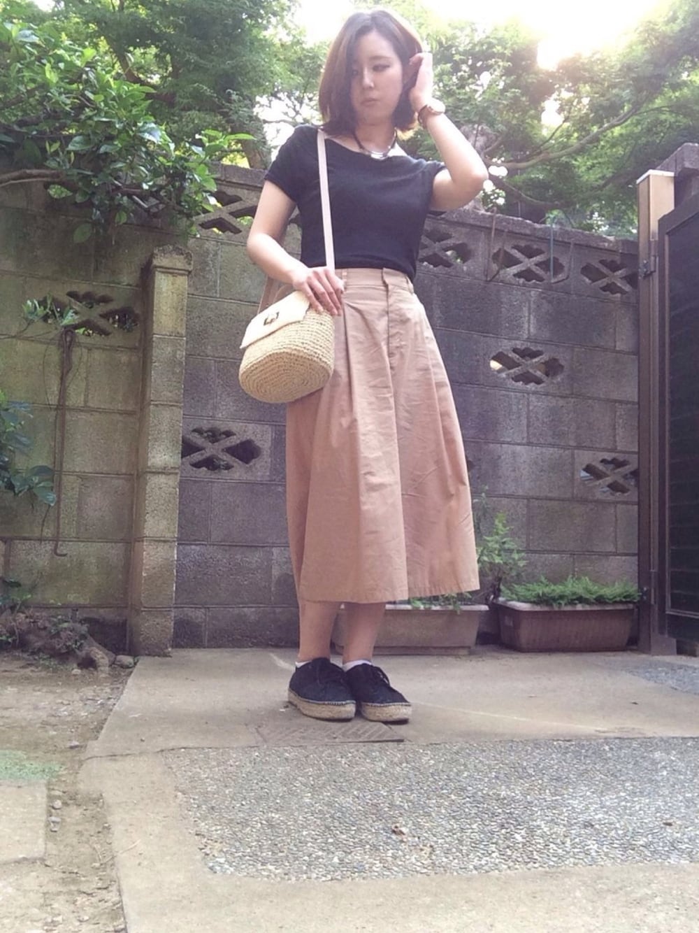 ベージュ系のパンツ、ベージュ系のショルダーバッグ、ブラック系のスニーカーを着用したレディースの夏コーディネートの1枚目の写真