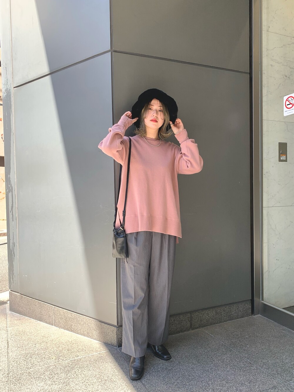 ピンク系のニット/セーター、グレー系のスラックス、ブラック系のショルダーバッグを着用したレディースの秋コーディネートの1枚目の写真