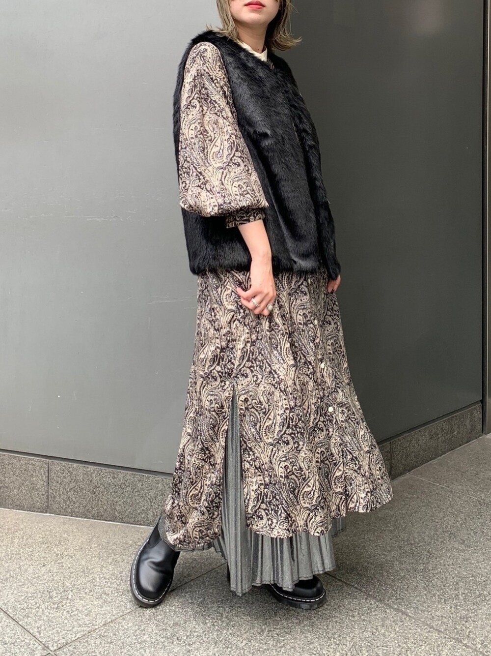 ブラック系のベスト、ブラック系のワンピース、シルバー系のスカートを着用したレディースの秋コーディネートの1枚目の写真