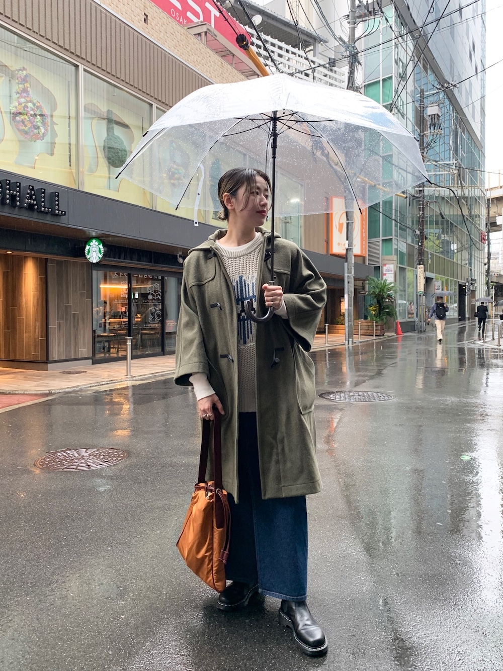 グリーン系のダッフルコート、ベージュ系のニット/セーター、ブルー系のデニムスカートを着用したレディースの秋コーディネートの1枚目の写真