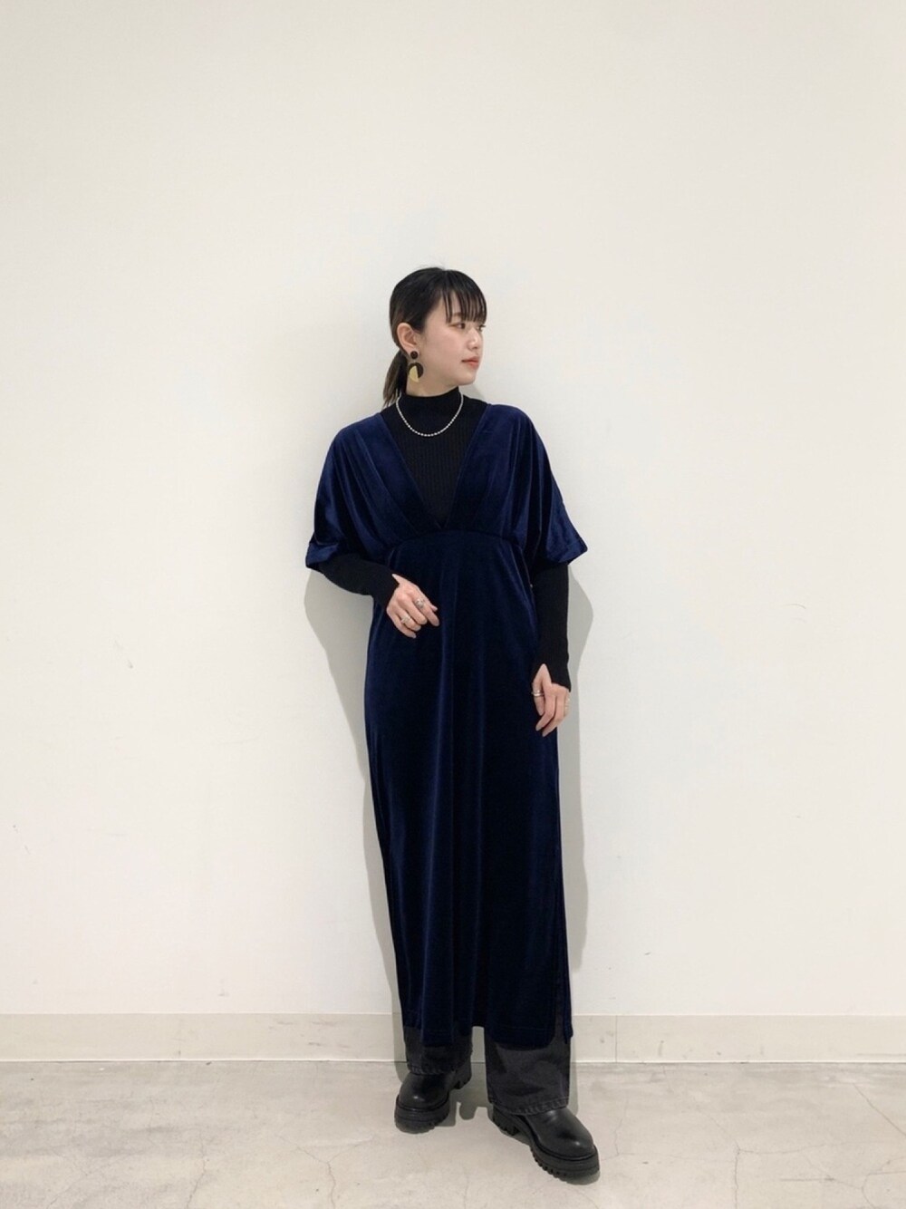 ブルー系のワンピース、ブラック系のニット/セーター、シルバー系のネックレスを着用したレディースの冬コーディネートの1枚目の写真