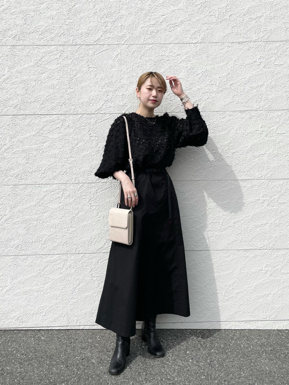 ブラック系のシャツ/ブラウス、ブラック系のスカート、ベージュ系のショルダーバッグを着用したレディースの春コーディネートの1枚目の写真