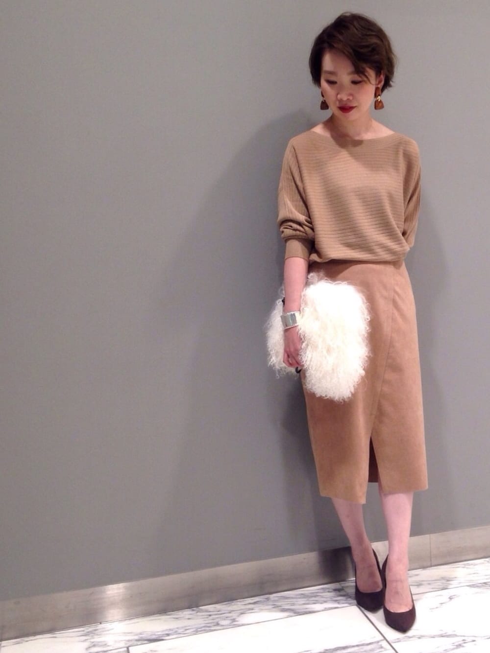 ホワイト系のショルダーバッグ、ブラウン系のパンプス、ベージュ系のスカートを着用したレディースの秋コーディネートの1枚目の写真