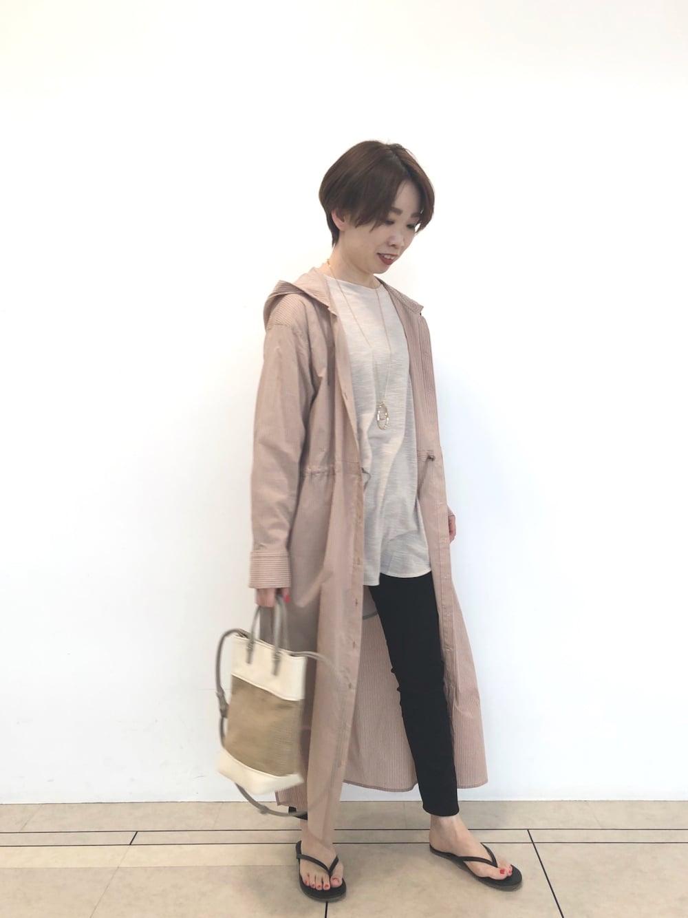 ブラウン系のワンピース、ベージュ系のTシャツ/カットソー、ブラック系のデニムパンツを着用したレディースの春コーディネートの1枚目の写真