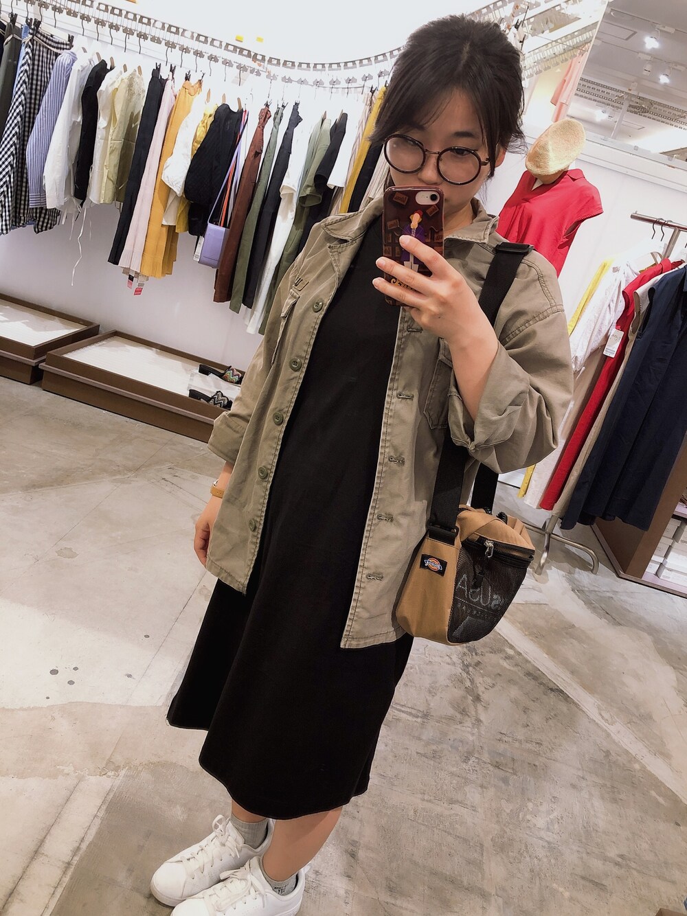 ブラック系のワンピース、ホワイト系のスニーカー、ブラック系のショルダーバッグを着用したレディースの春コーディネートの1枚目の写真